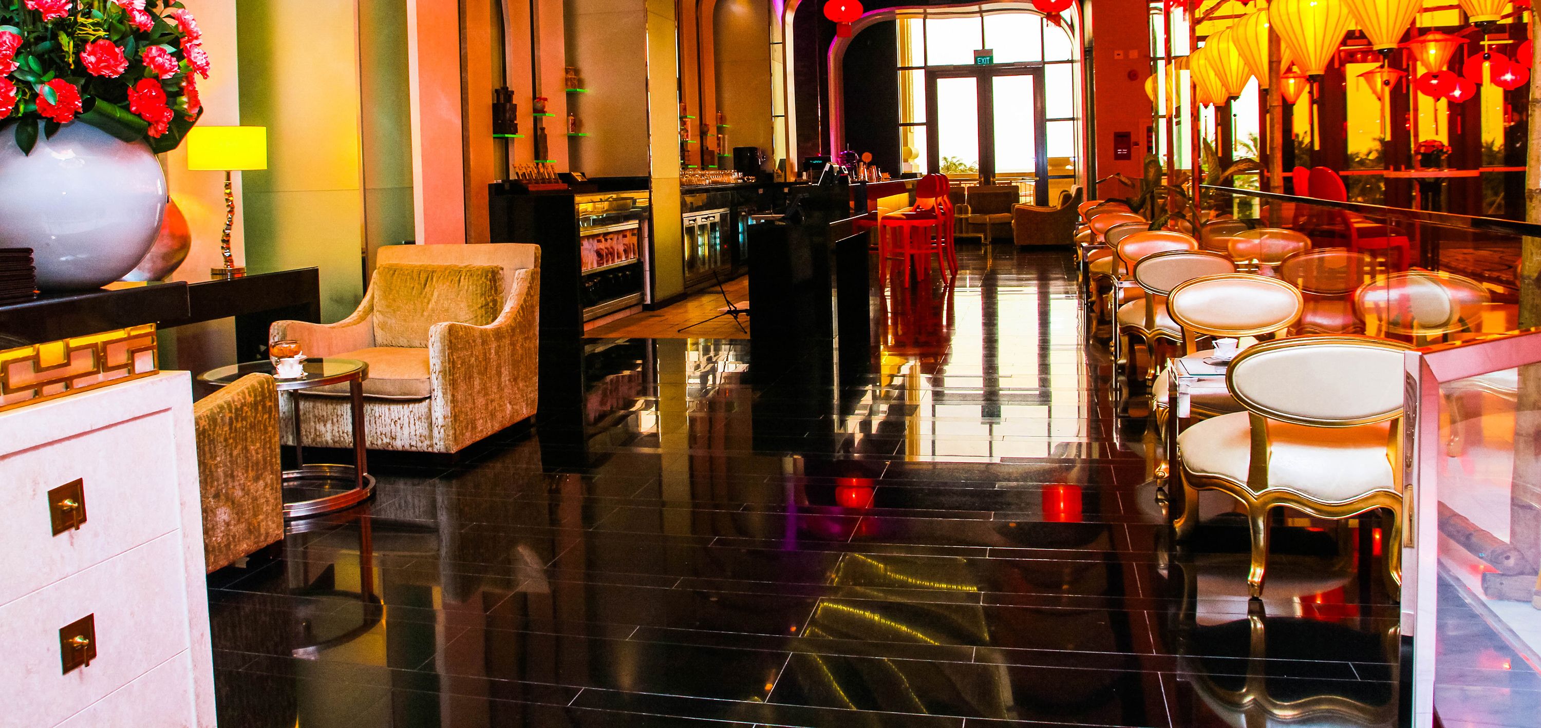 A hotel lobby with a bar, seating area, and a large vase of flowers.