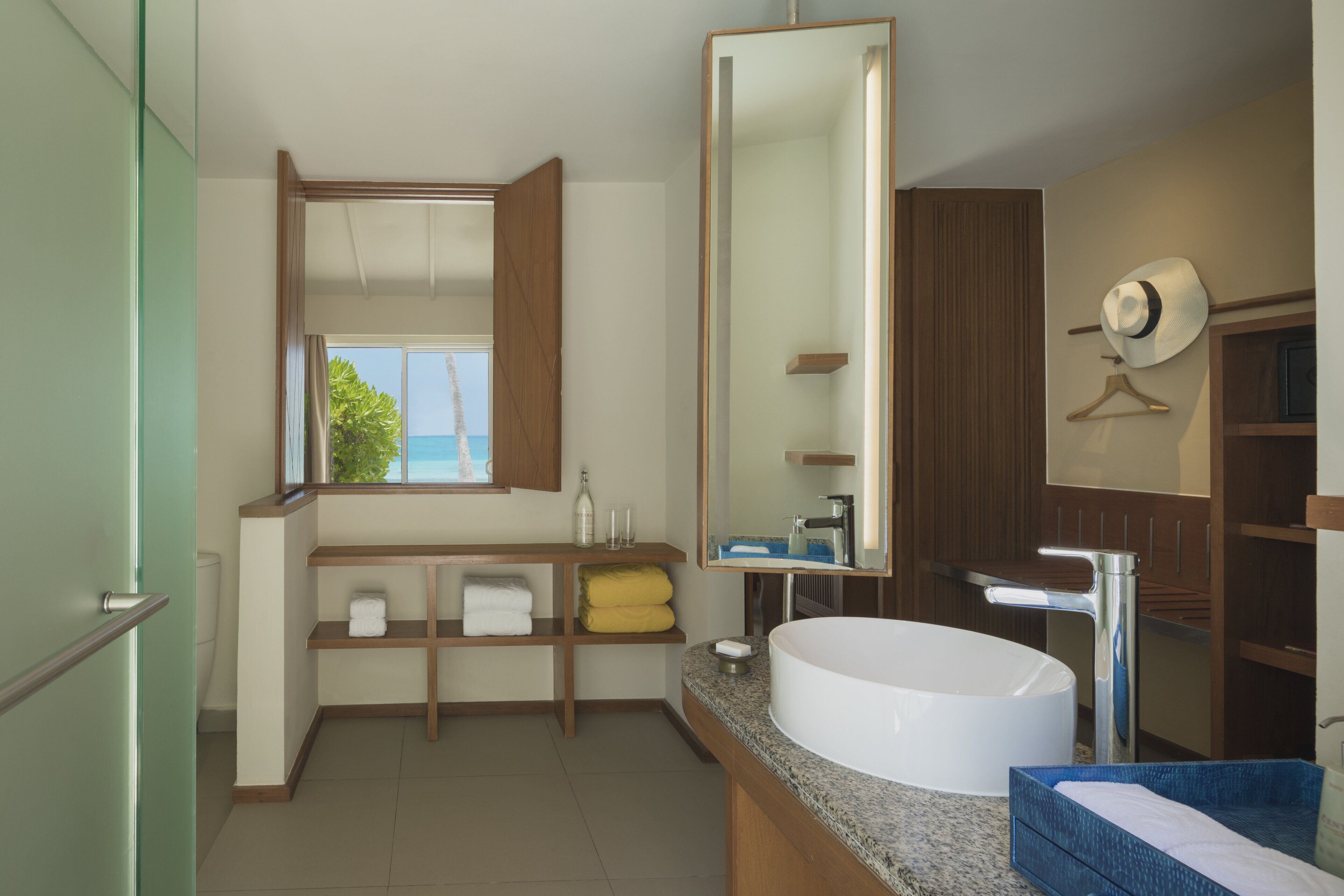 Une salle de bain moderne avec un grand miroir, un lavabo blanc et des étagères en bois.
