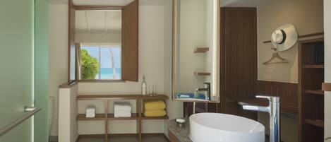 A modern bathroom with a large mirror, a white sink, and wooden shelves.
