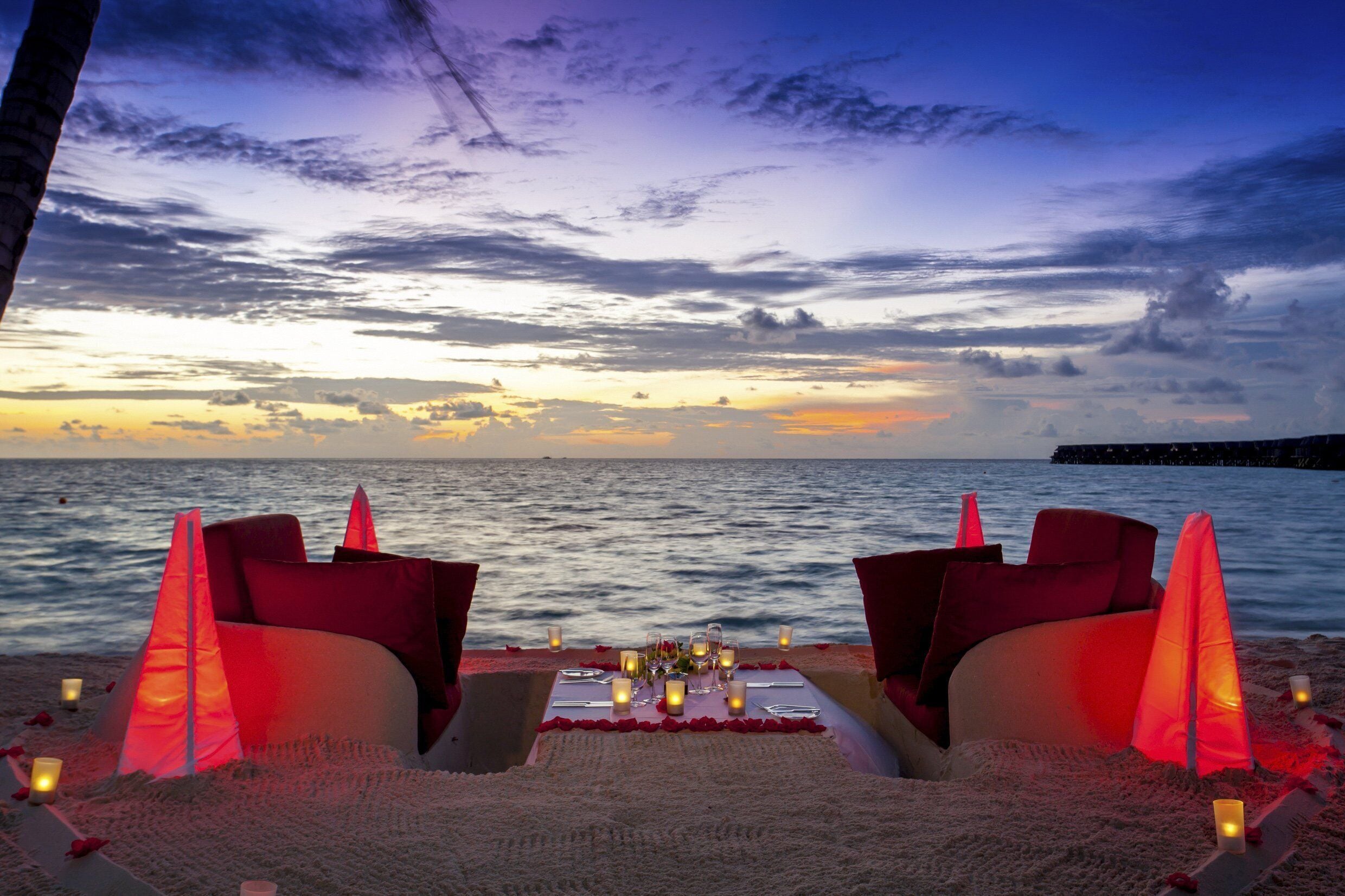 A beachside dining setup with a table set for two, overlooking the sea.