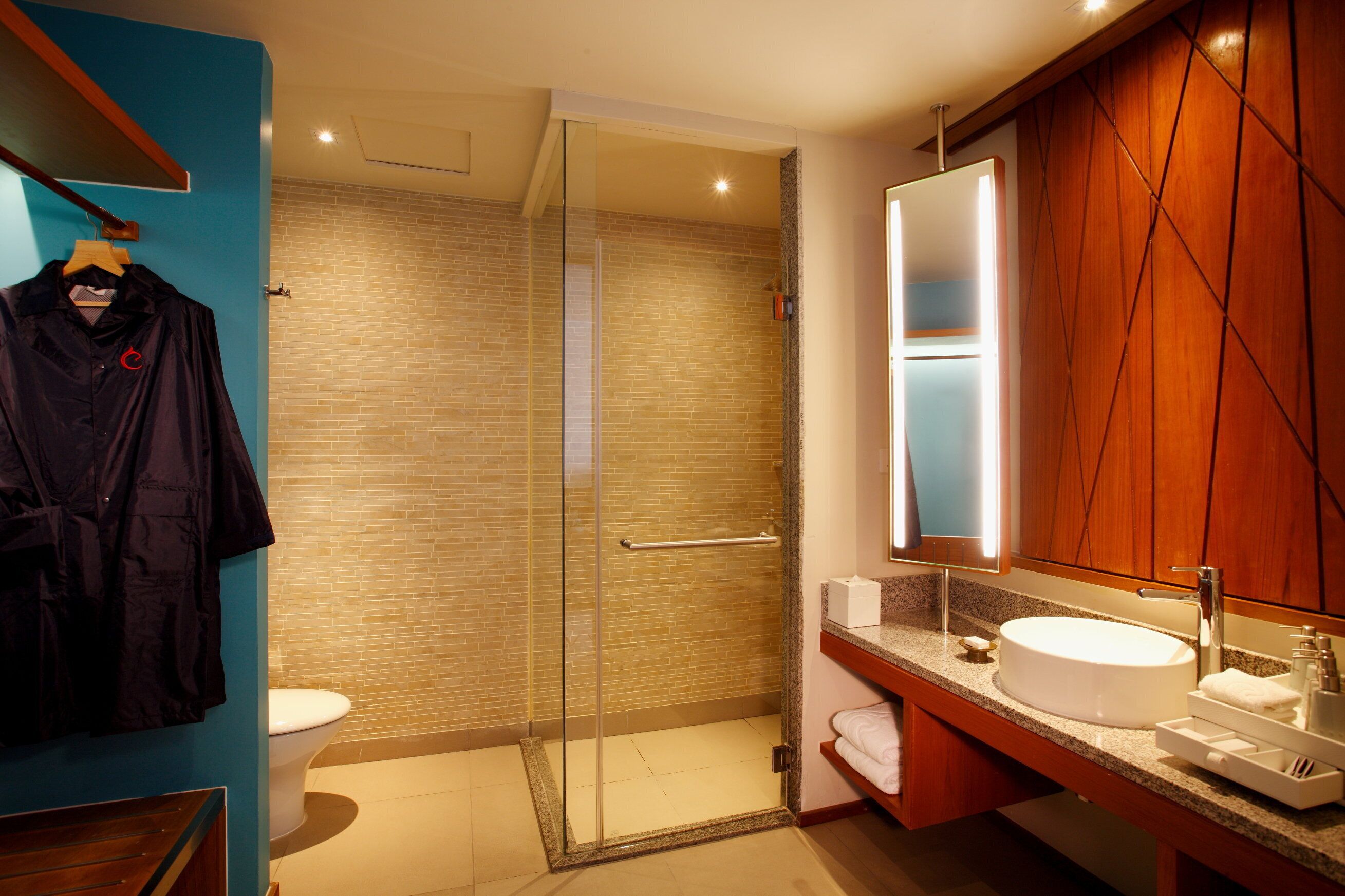 A modern bathroom with a glass-enclosed shower, a white sink, and a wooden vanity.