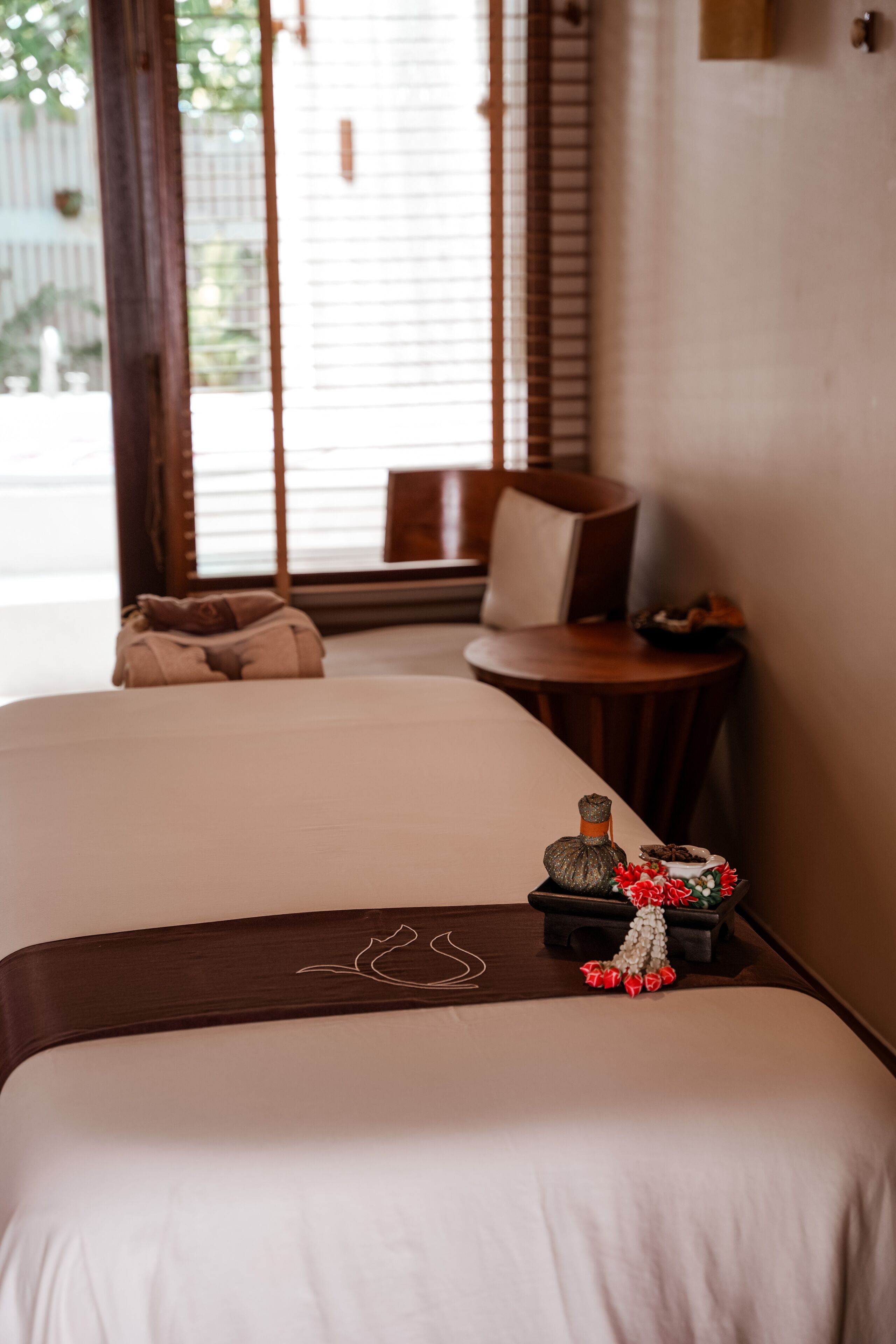A hotel room with two beds, a small table, and a chair.