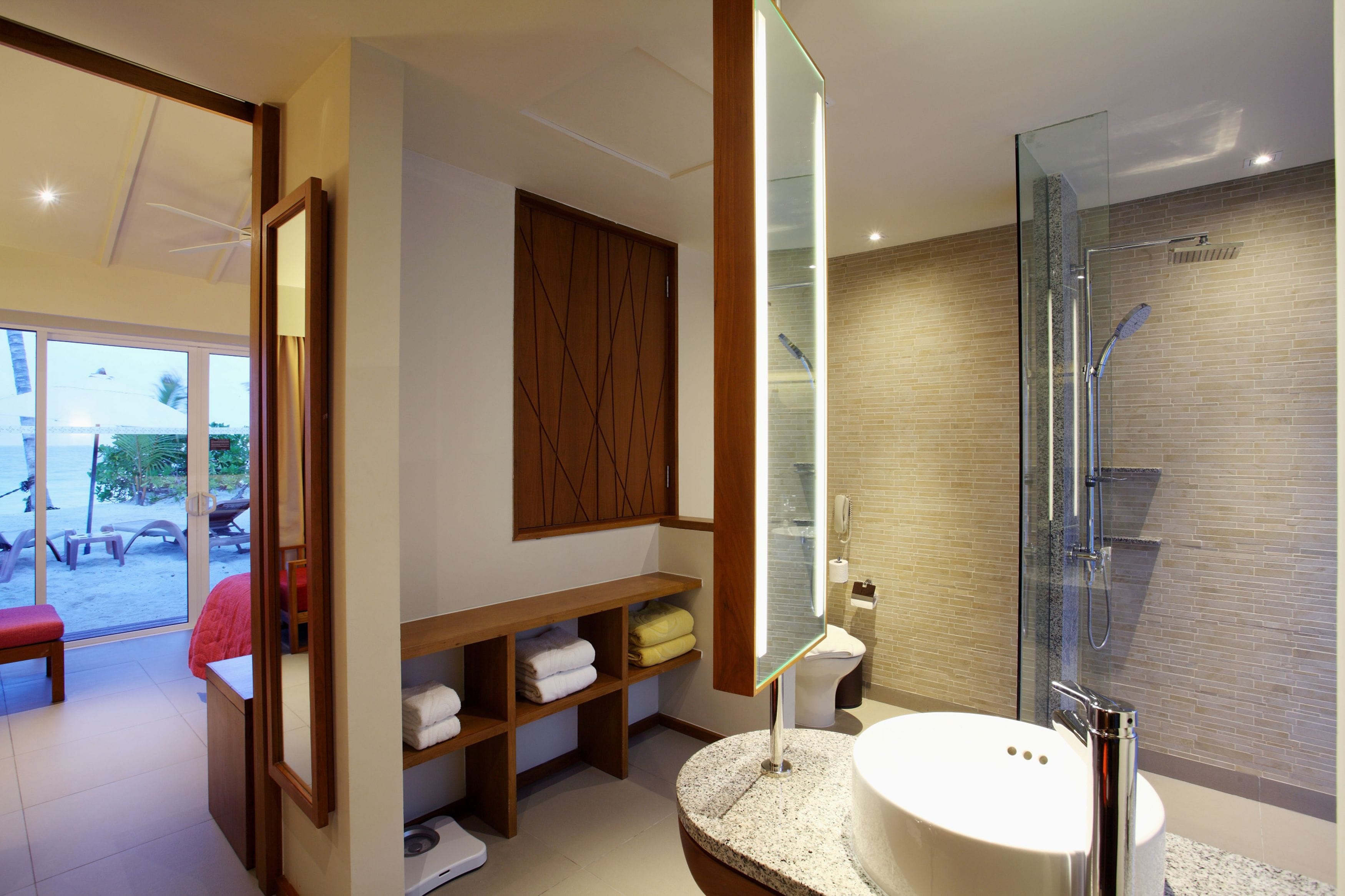 A modern bathroom with a glass-enclosed shower, a round sink, and a wooden vanity with shelves.