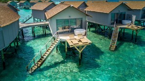 Bungalows sobre el agua con aguas azul turquesa, pasarelas de madera y una bañera de hidromasaje.