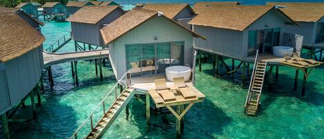 Overwater bungalows with clear blue water, wooden walkways, and a hot tub.