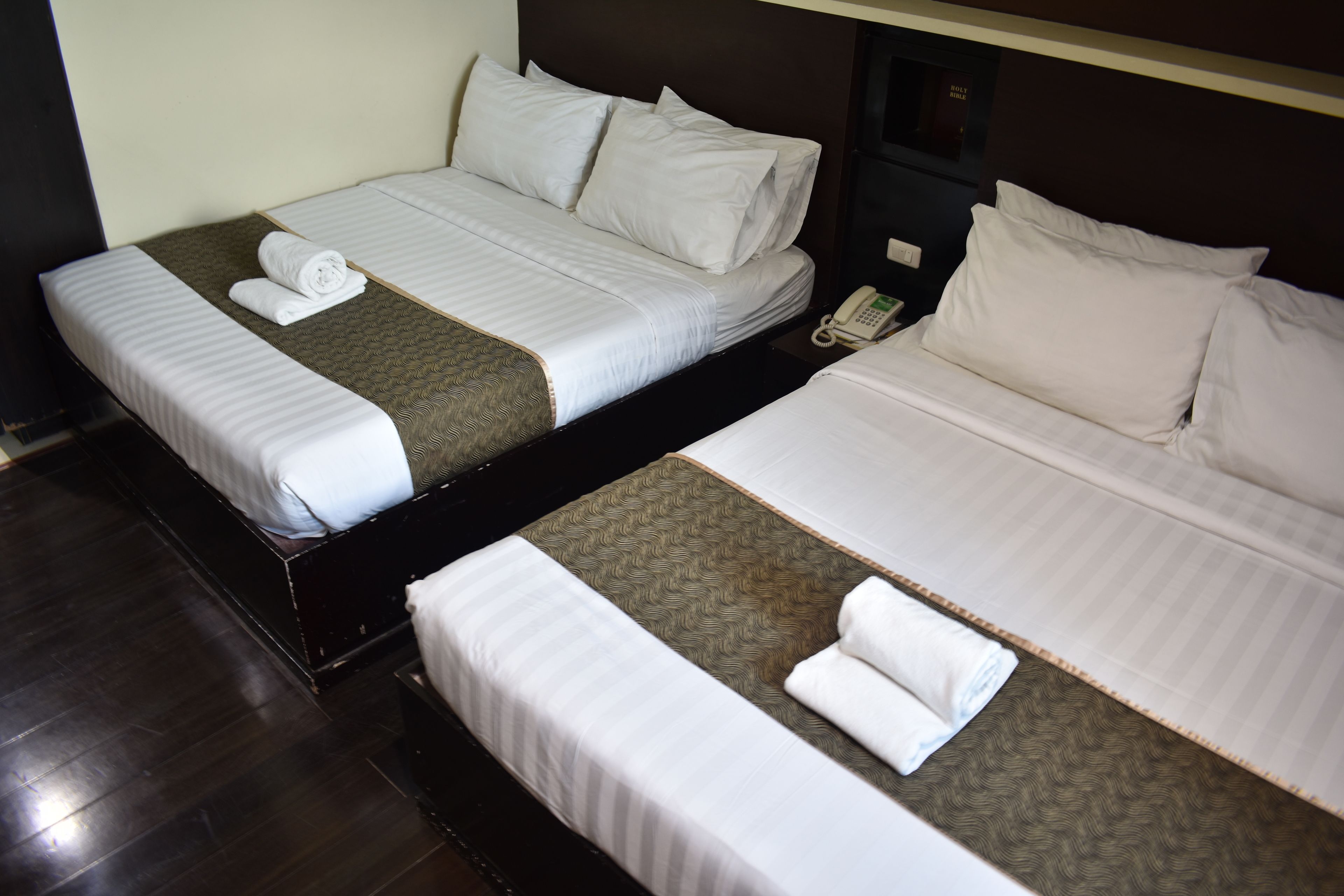 Two single beds with white linens and a telephone on the nightstand.