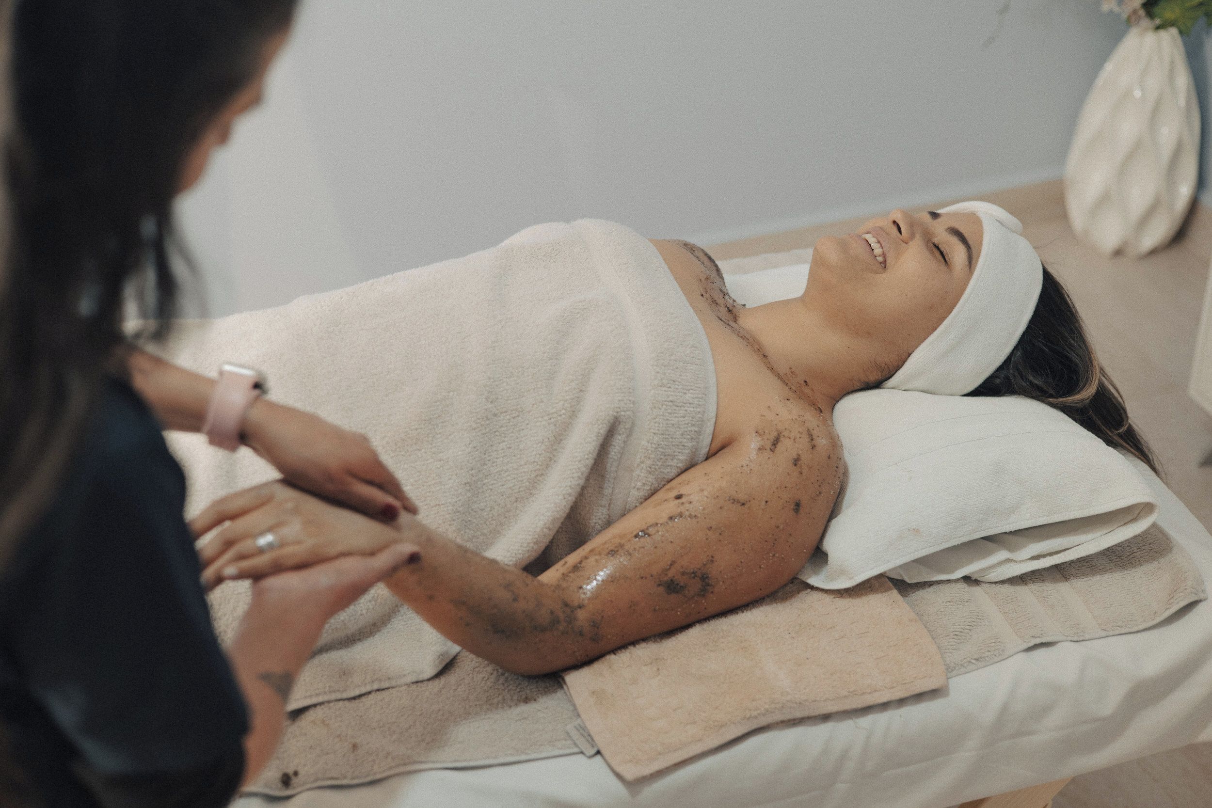 A person lying on a massage table with a towel covering their upper body, receiving a massage.