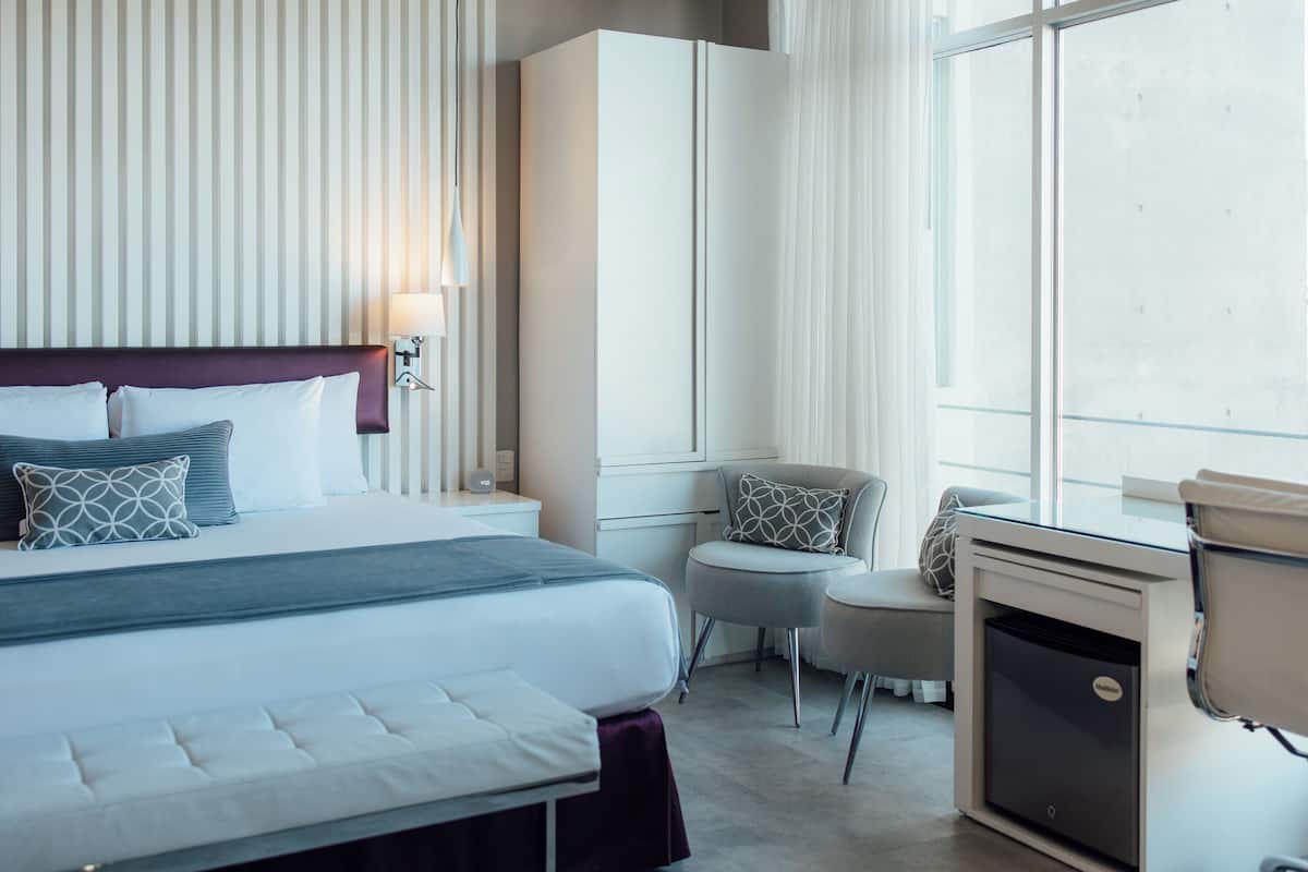 Una habitación de hotel con una cama grande, un escritorio, una silla y un armario.