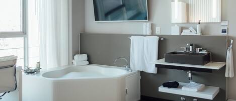 Un baño moderno con una bañera grande, un tocador con lavamanos y un espejo amplio.