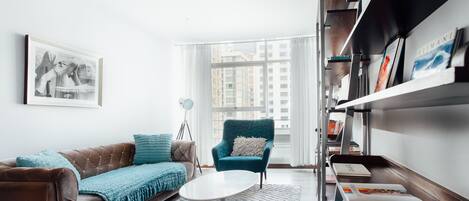 A modern living room with a brown sofa, teal armchair, and a white coffee table.