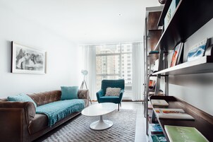 Una sala de estar moderna con un sofá marrón, un sillón verde azulado y una mesa de centro blanca.