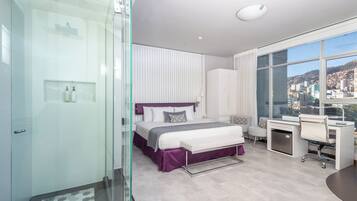 Un dormitorio moderno con una cama grande, un escritorio y vistas a un paisaje urbano.