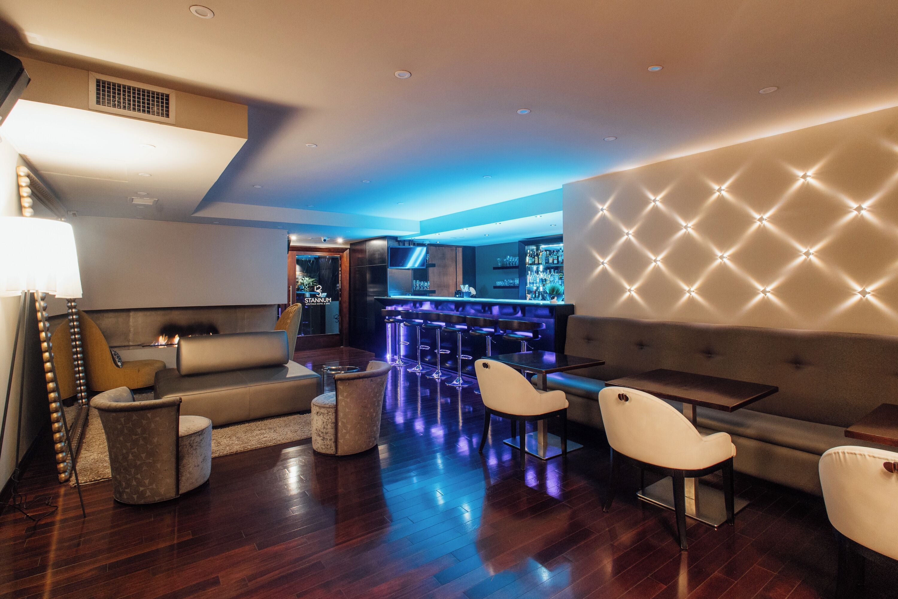 A modern lounge area with a bar, seating, and a fireplace.