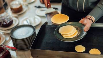 A person cooking pancakes on a griddle.