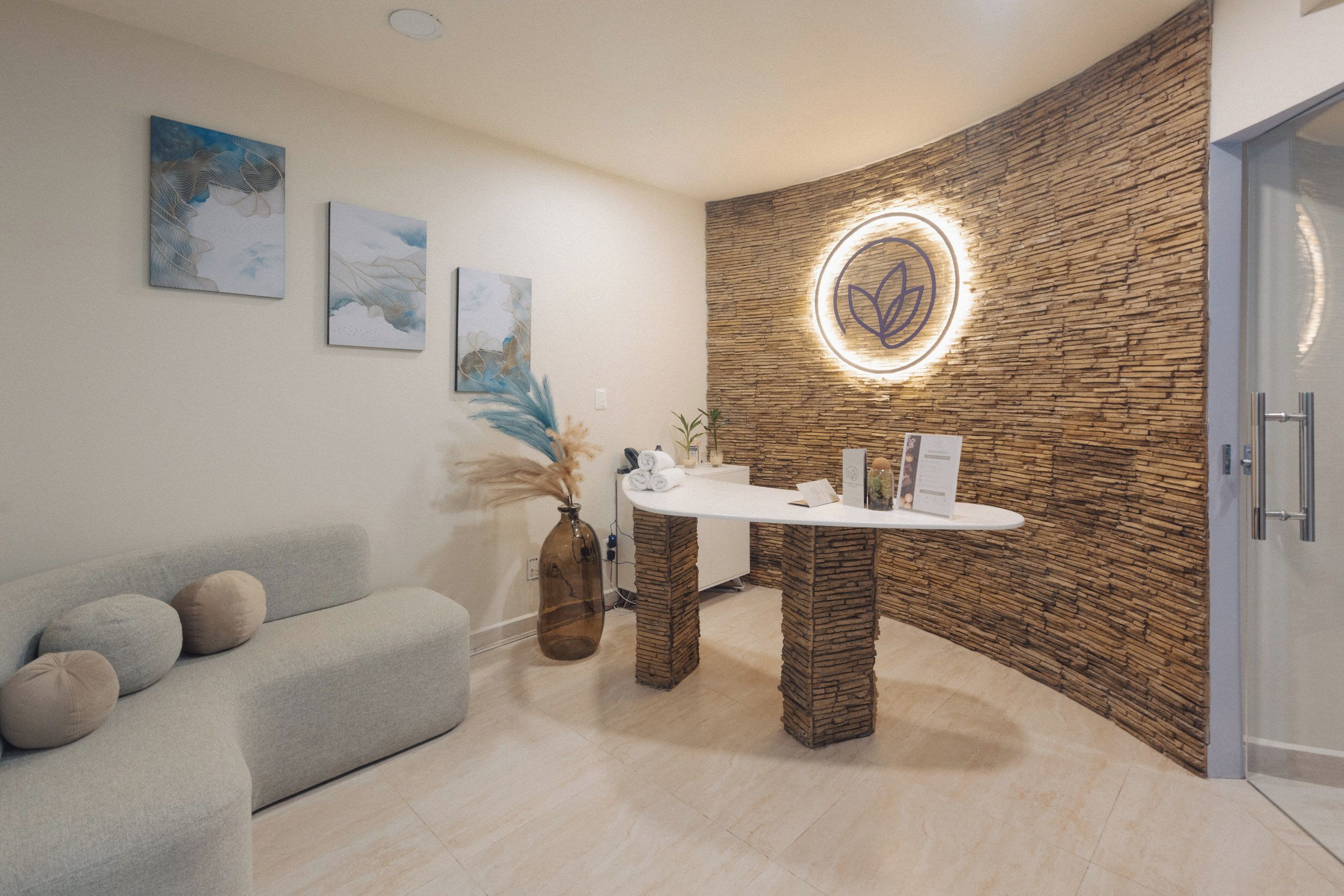A reception area with a stone wall, a reception desk, a couch, and framed artwork on the wall.