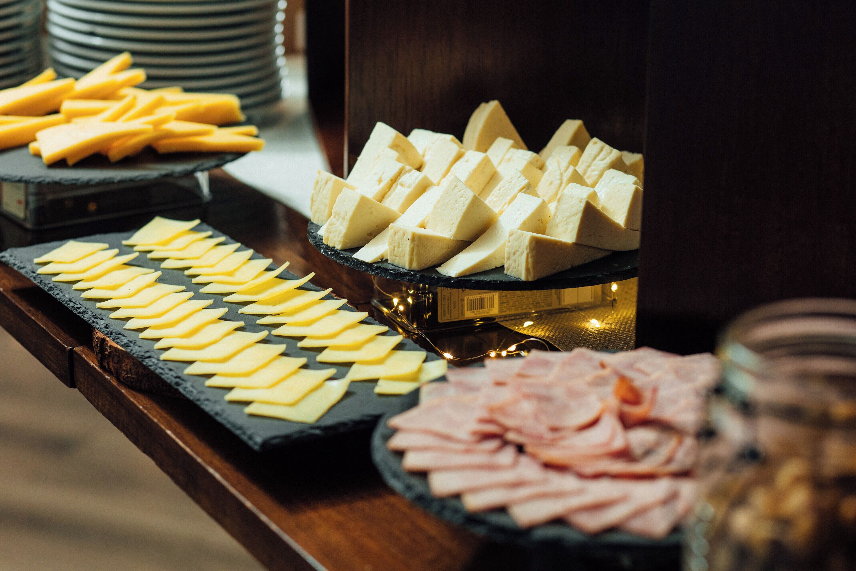 Una mesa de buffet con varios quesos y embutidos.