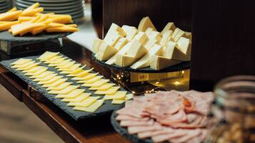 Una mesa de buffet con varios quesos y embutidos.