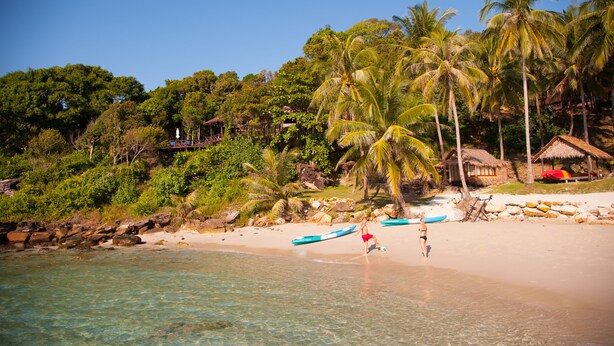 A beach with clear water, palm trees, and a hut. - Koh Kood Beach Resort (Ko Kood)