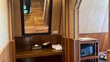 A wooden interior with a bench, a mirror, and a microwave shelf.