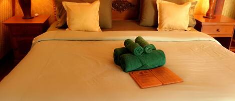 A neatly made bed with a wooden headboard, two bedside tables with lamps, and a folded towel on the bed.