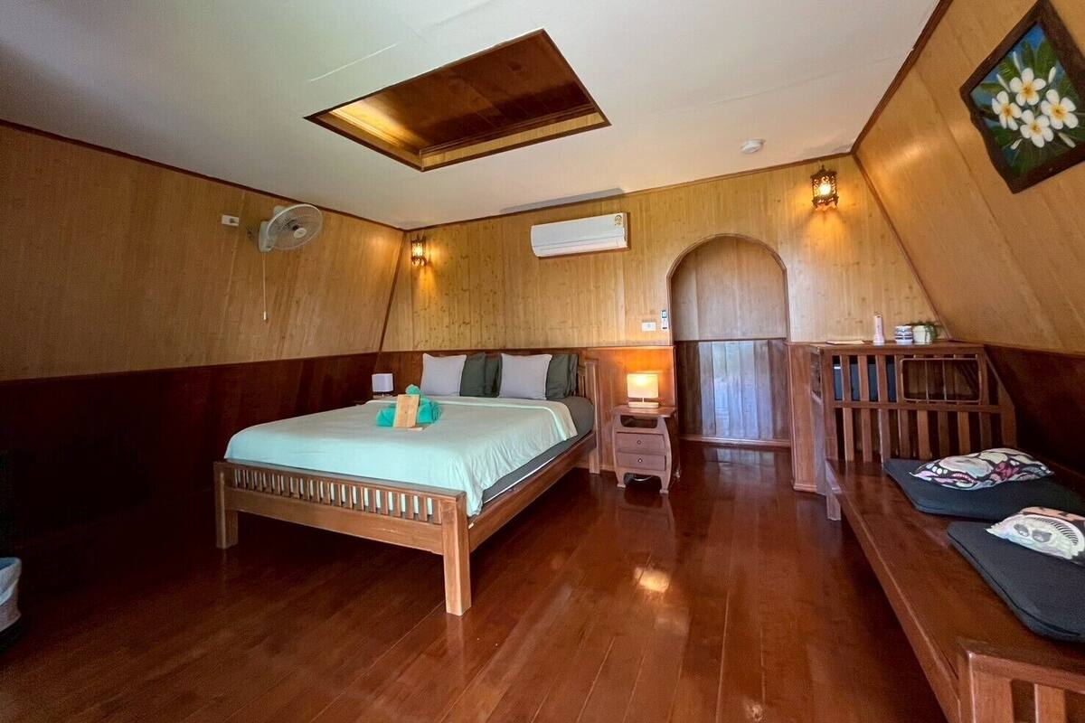 Une pièce en bois avec un lit, un bureau et un petit coin salon.