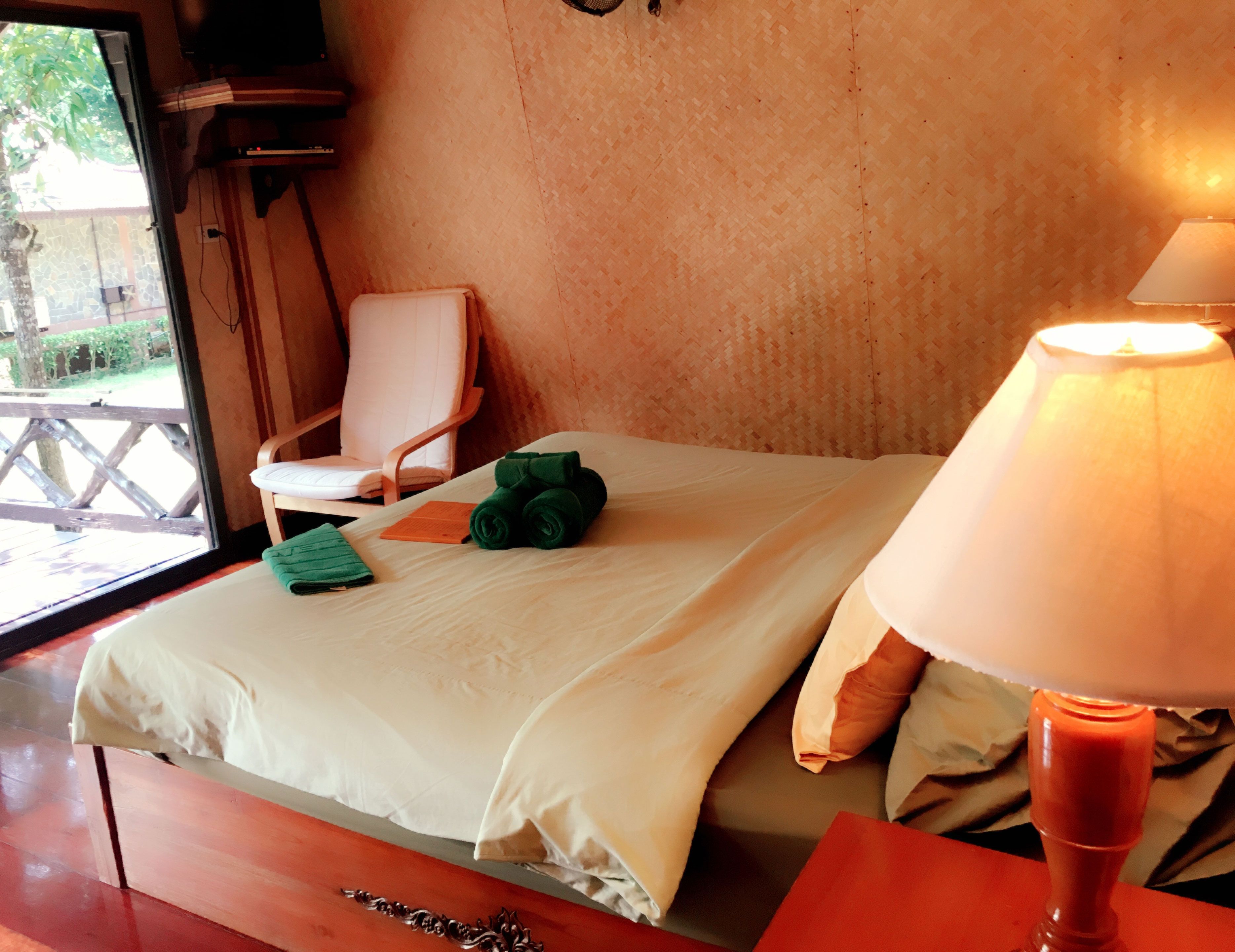 Habitación de hotel con cama, una silla, una lámpara y vistas al exterior.