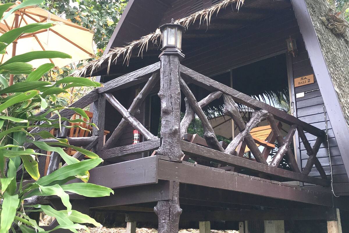 Une structure en bois, dotée d’un toit de chaume et d’un balcon avec une balustrade.