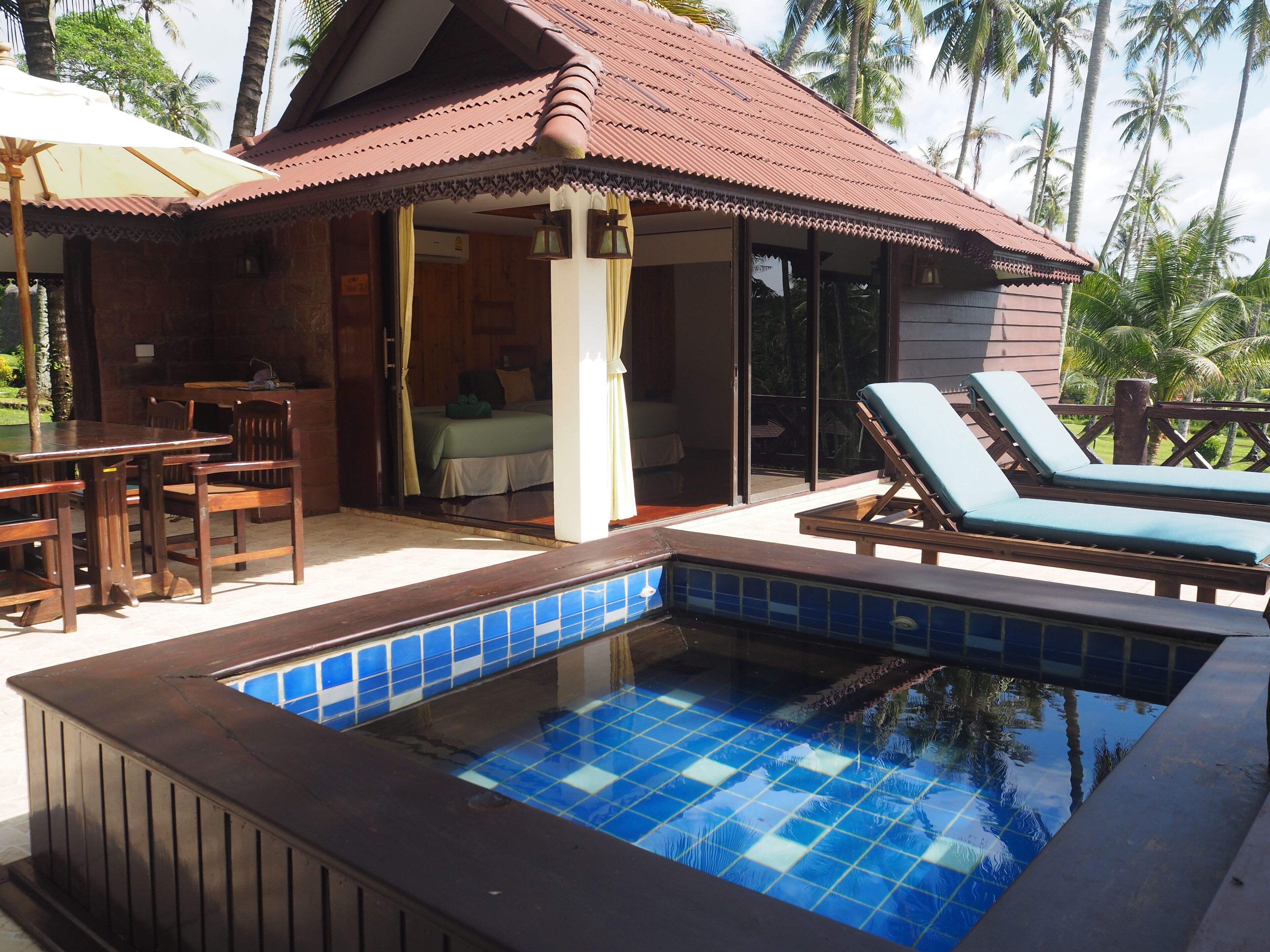 Un espace piscine doté d’une piscine carrelée, de chaises longues et d’une terrasse en bois.