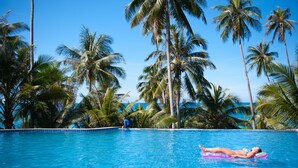 A pool with clear blue water, surrounded by tall palm trees and a clear sky. - Koh Kood Beach Resort (Ko Kood)