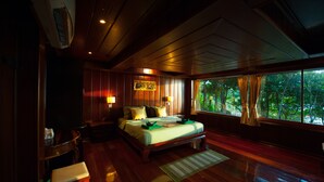 A bedroom with a large bed, wooden walls, and a window with curtains. - Koh Kood Beach Resort (Ko Kood)