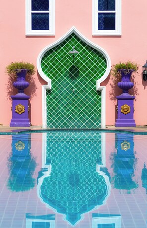 A building with a green gate, two purple flower pots, and a pool reflecting the gate. - Rasa Boutique Hotel (Chiang Rai)