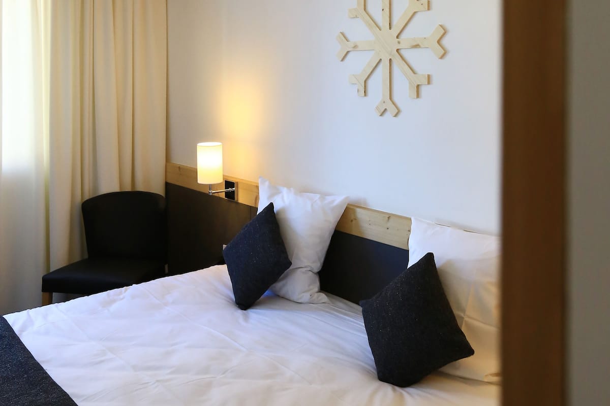 A hotel room with a bed, a nightstand, a lamp, and a wall decoration.