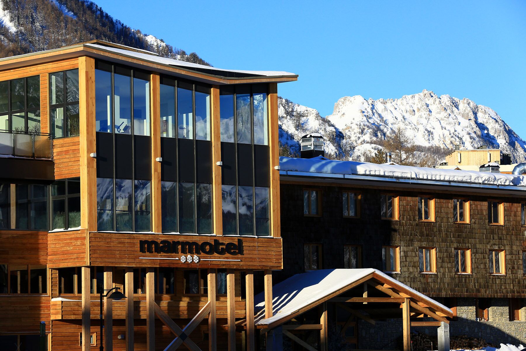 A modern building with large windows and a wooden facade, labeled "marmotel."