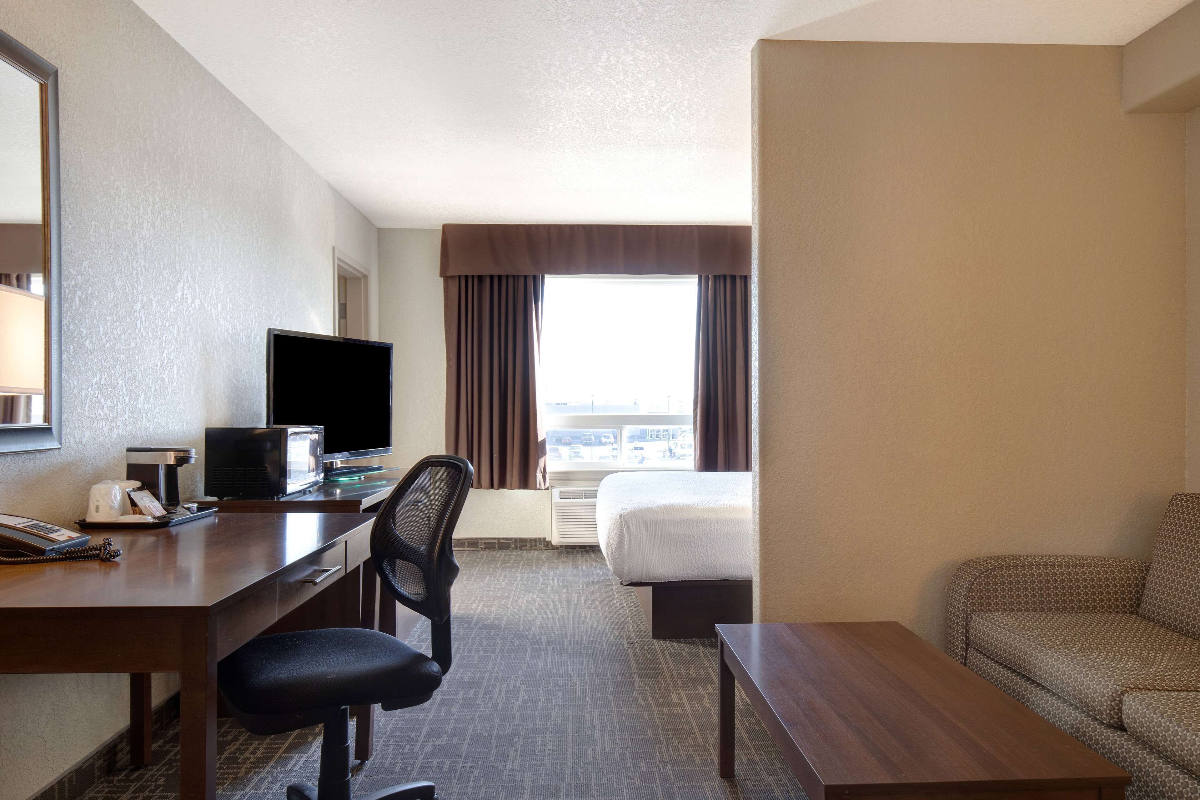 A hotel room with a desk, chair, bed, and a sofa.