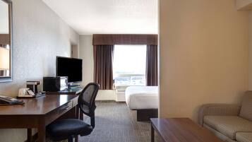 A hotel room with a desk, chair, bed, and a sofa.