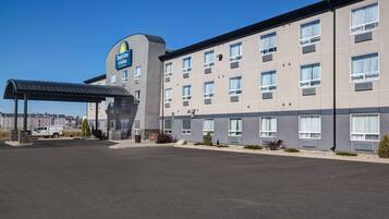 Edificio de Days Inn & Suites con una zona de estacionamiento techada y una camioneta blanca estacionada afuera.