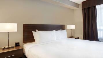 A hotel room with a large bed, two bedside tables, a nightstand, a digital clock, and a window with curtains.