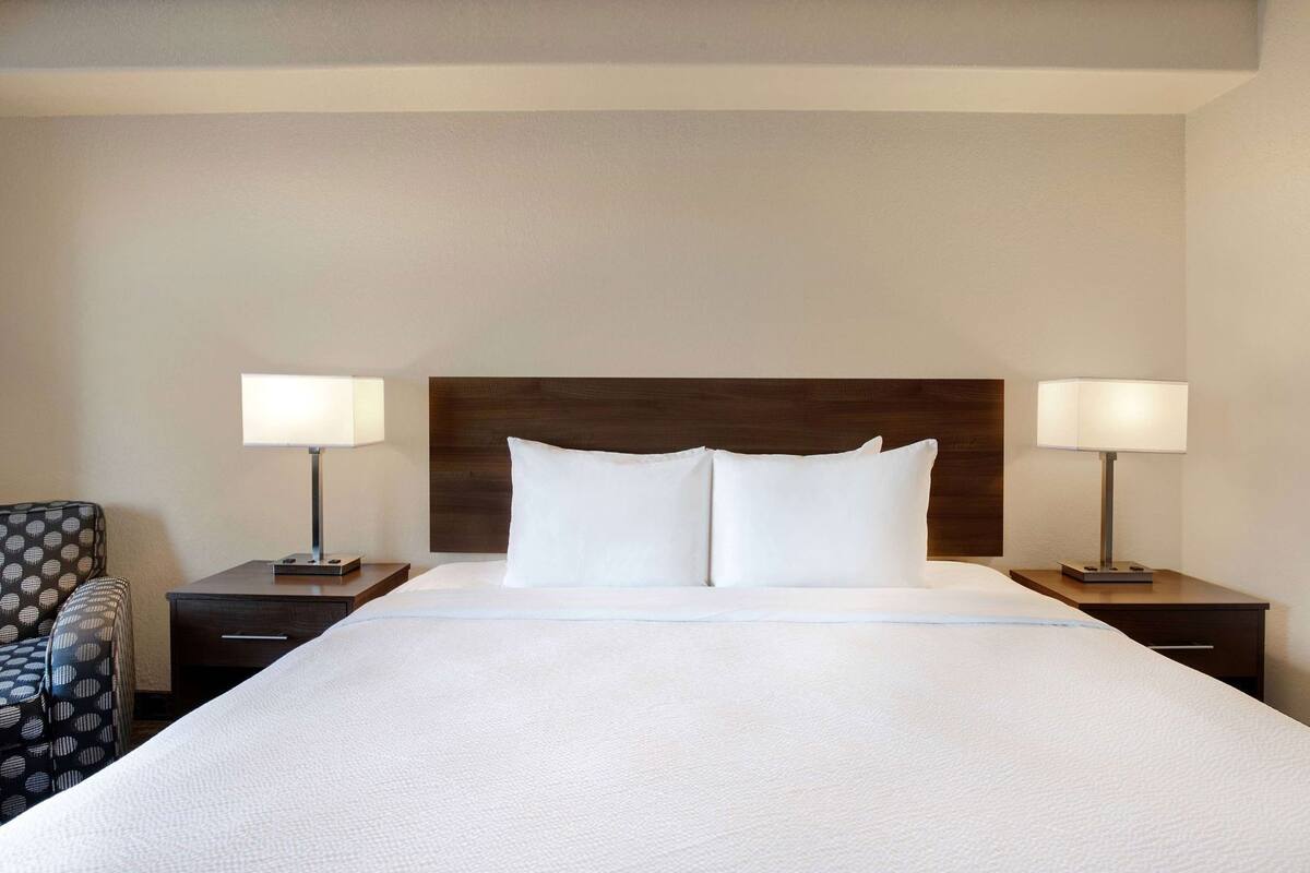 A hotel room with a large bed, two bedside tables, a chair, and a nightstand.