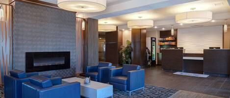 En moderne lobby med blå siddepladser, et fladskærms-tv og en reception.