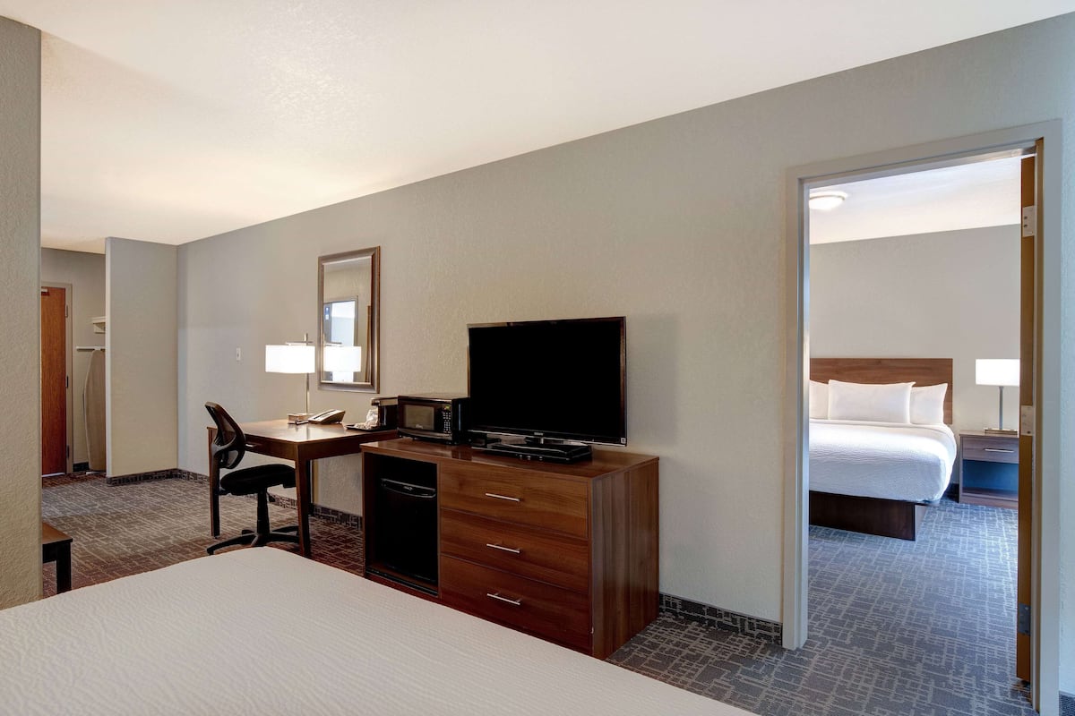 A hotel room with a bed, a desk with a chair, a television, and a dresser.