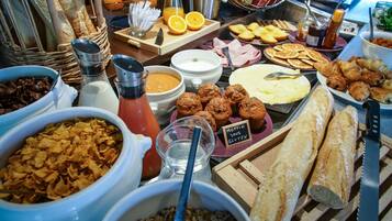 Un bufé con diversos alimentos, incluyendo pan, muffins y frutas.