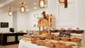 A buffet setup with various breads and pastries displayed on a wooden stand and in wicker baskets, with a sign reading "Bakery". - Ramada by Wyndham Tashkent (Tashkent)