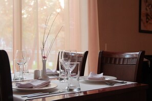 Mesa posta com pratos, copos e um vaso com galhos.