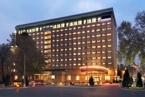 Um hotel com vários andares e uma placa chamativa com a inscrição 'RAMADA' na entrada.