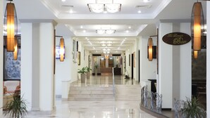 A spacious, well-lit hotel lobby with a marble floor, large potted plants, and a reception desk in the center. - Ramada by Wyndham Tashkent (Tashkent)