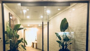 L’entrée d’un hôtel avec une porte en verre, des plantes en pot et une enseigne indiquant : « Polynesian Residences Hotel | Waikiki ».