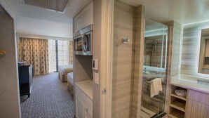 Une chambre d’hôtel équipée d’un lit, d’un bureau, d’un four à micro-ondes, d’une douche et d’une coiffeuse avec un miroir.