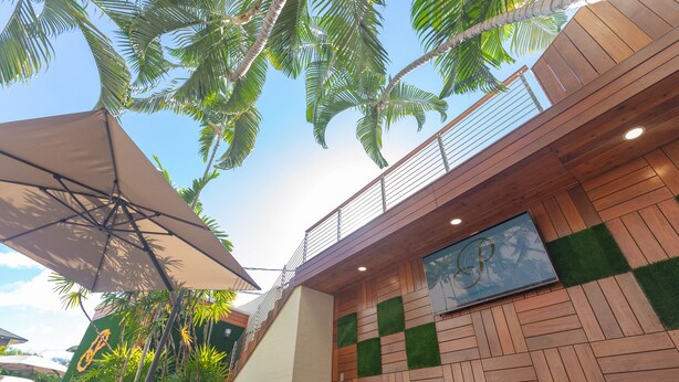 Un espace extérieur moderne avec un plancher en bois, un grand parasol et une vue sur le ciel.