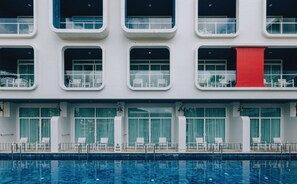 Ein Hotel mit Pool, mehreren Balkonen und einer markanten roten Säule.