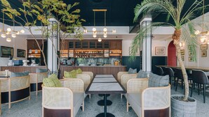 Een restaurant met rieten meubels, een bar en potplanten.